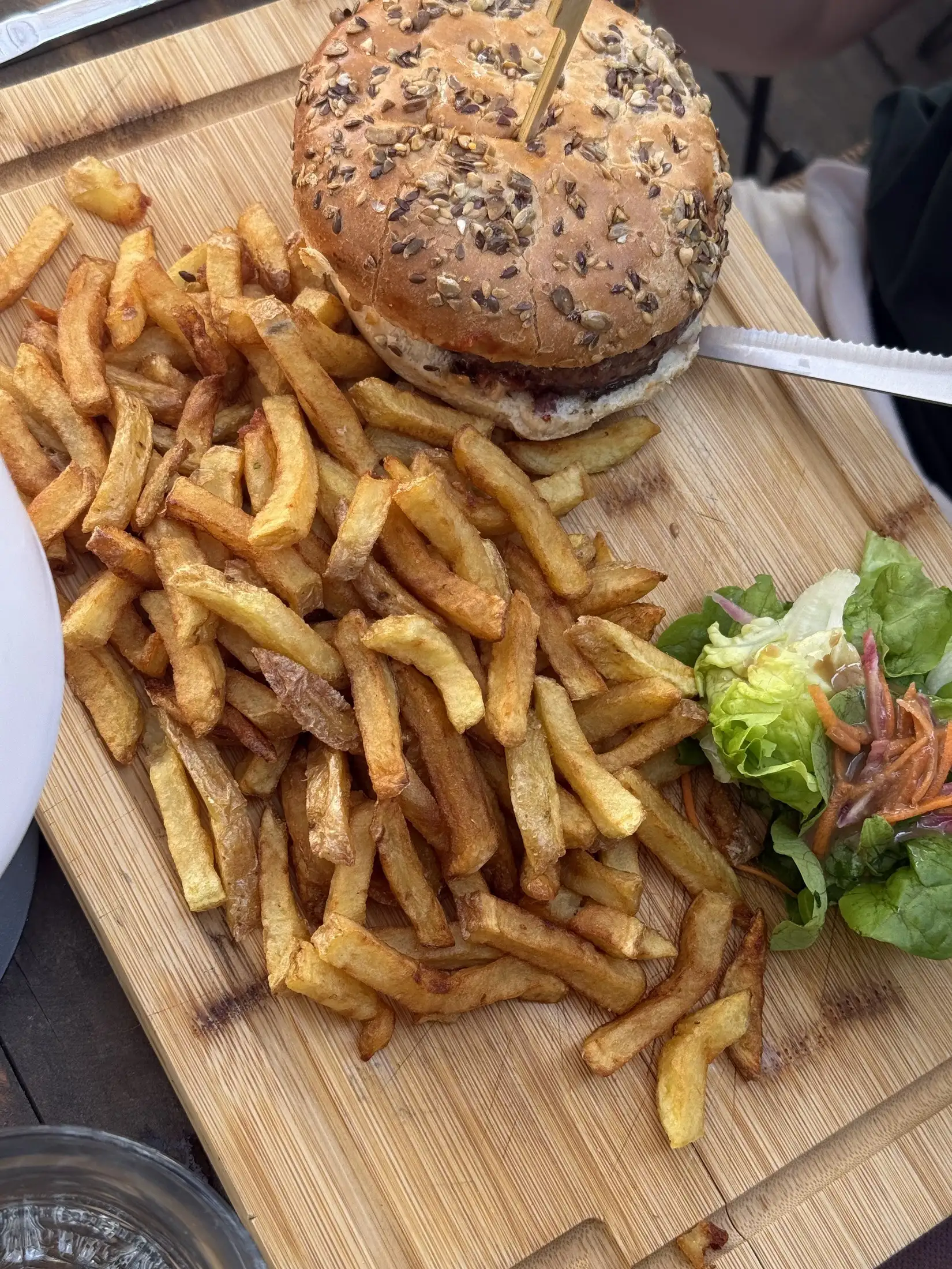 Burger au pain aux graines et frites maison, servis sur planche