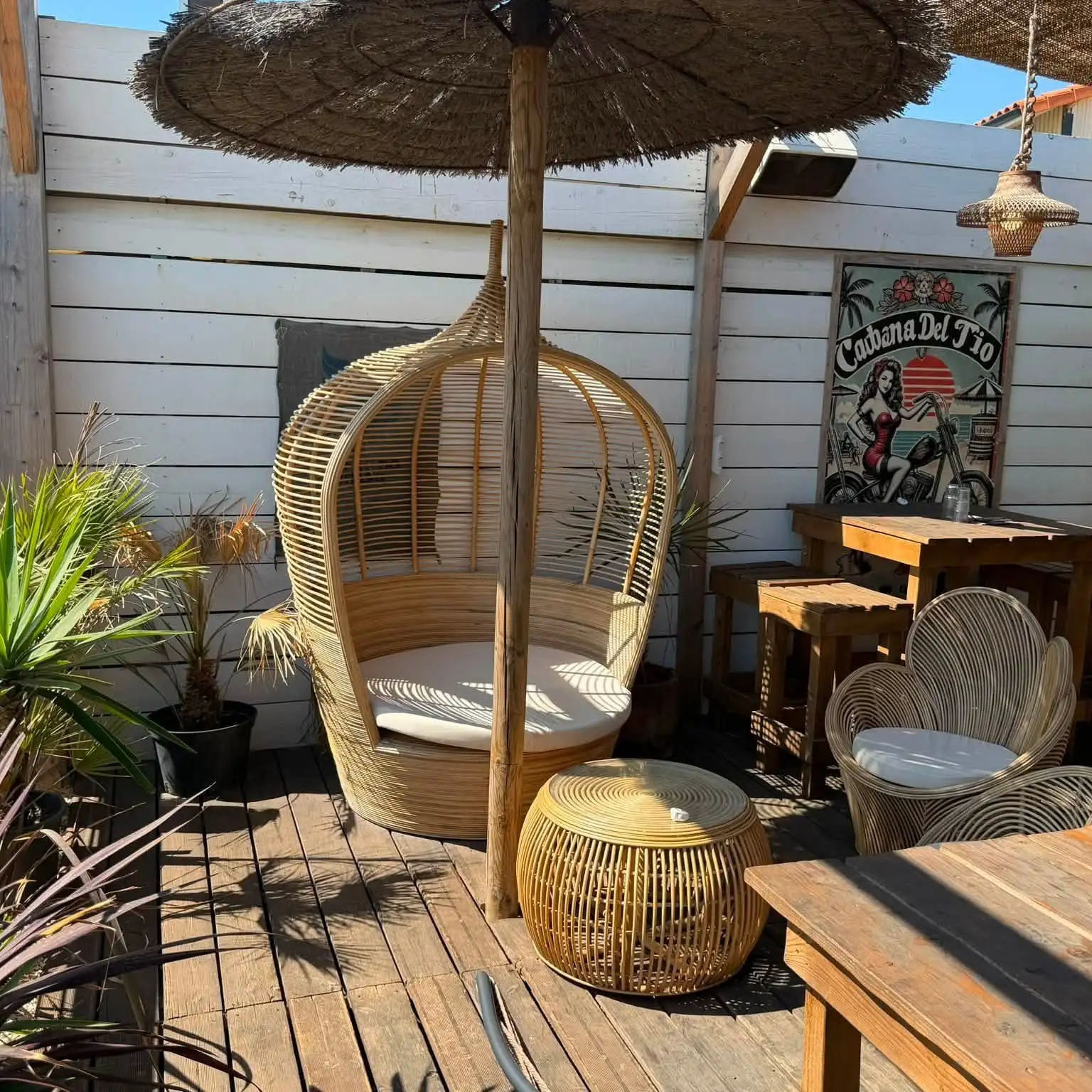 Fauteuil suspendu en rotin dans un coin de la terrasse en bois