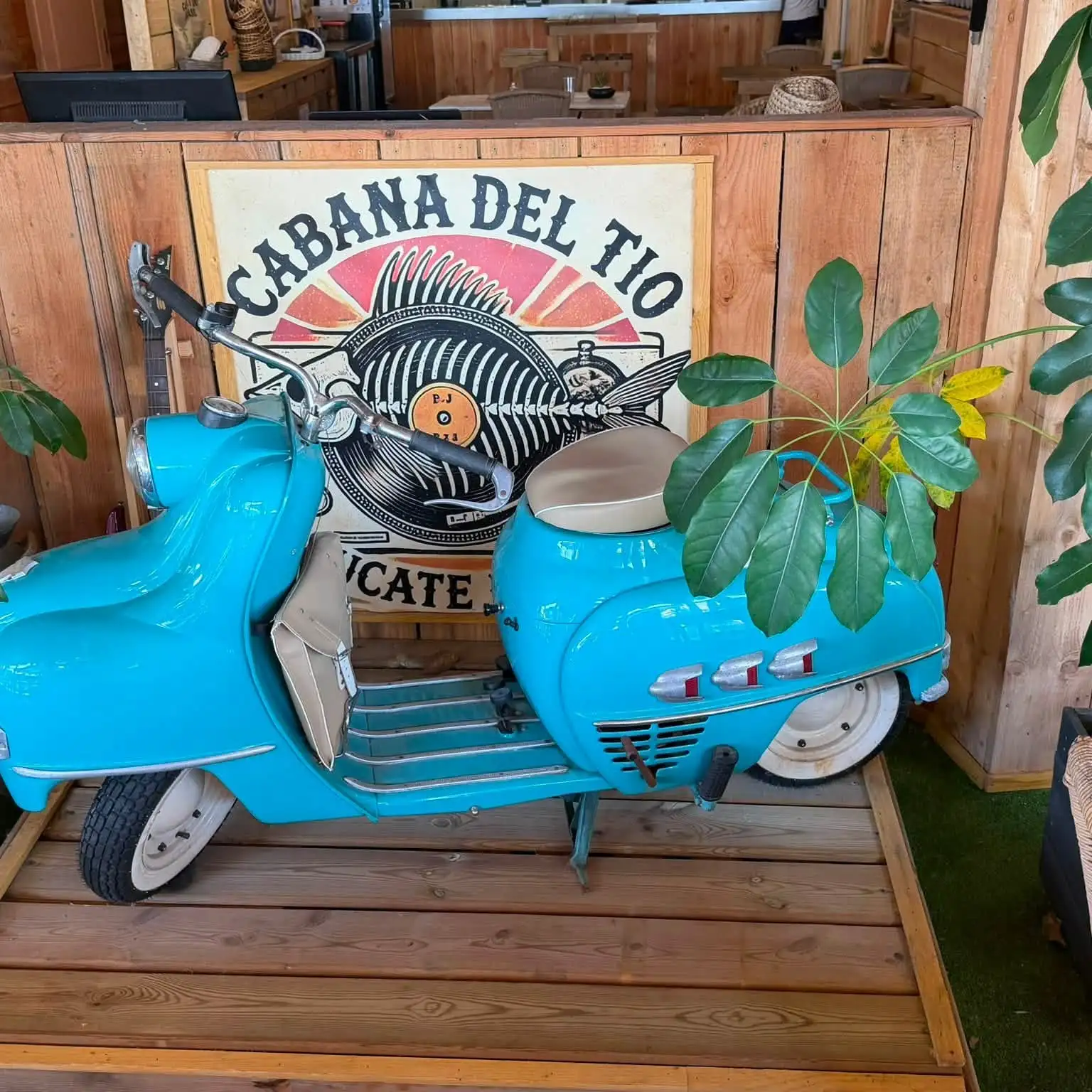 Une Vespa bleue installée en décor sous l'enseigne du restaurant