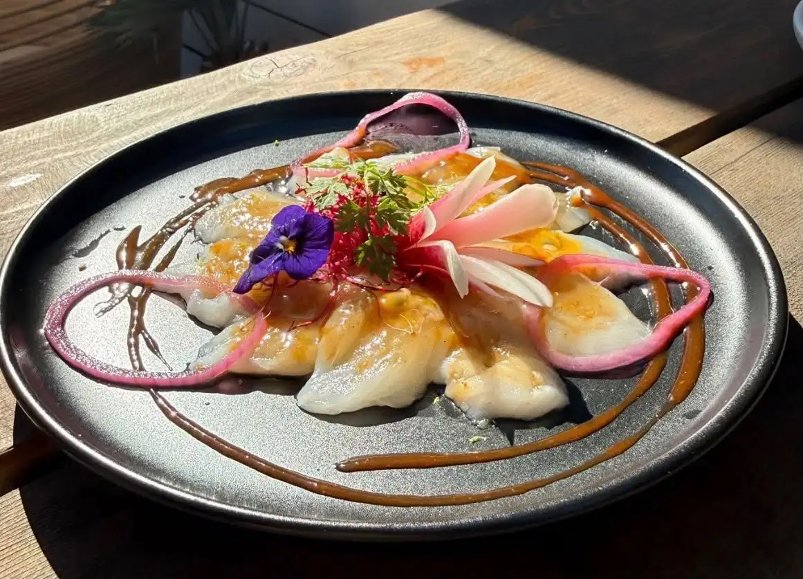 Carpaccio de poisson aux agrumes, oignon rouge et pousses